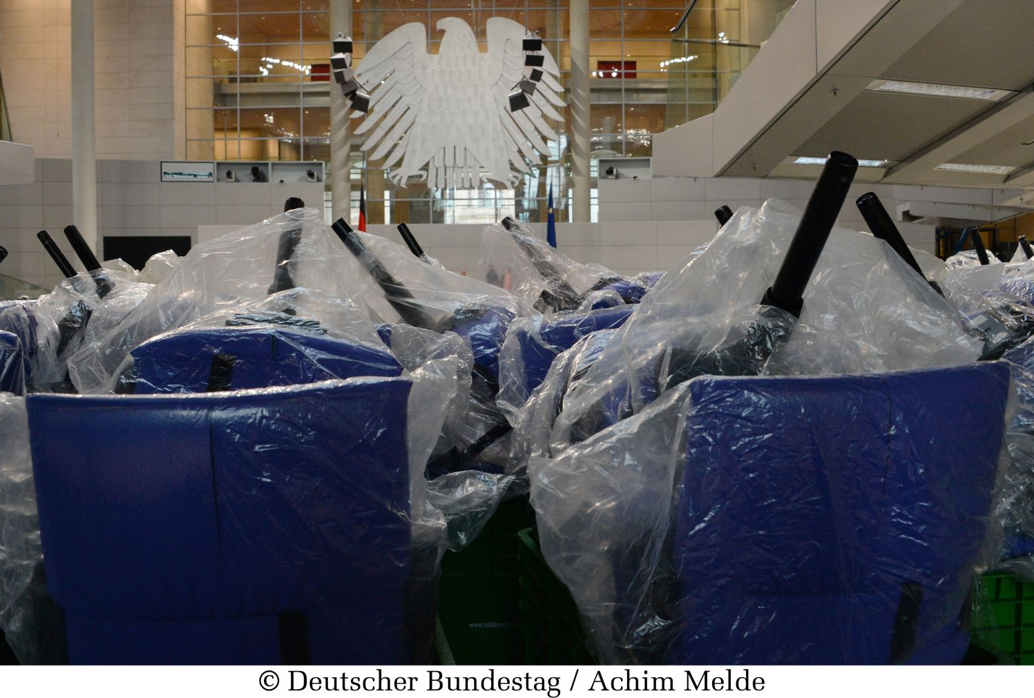 Der Plenarsaal des Bundestages während eines Umbaus. Eingepackte Stühle liegen übereinander.